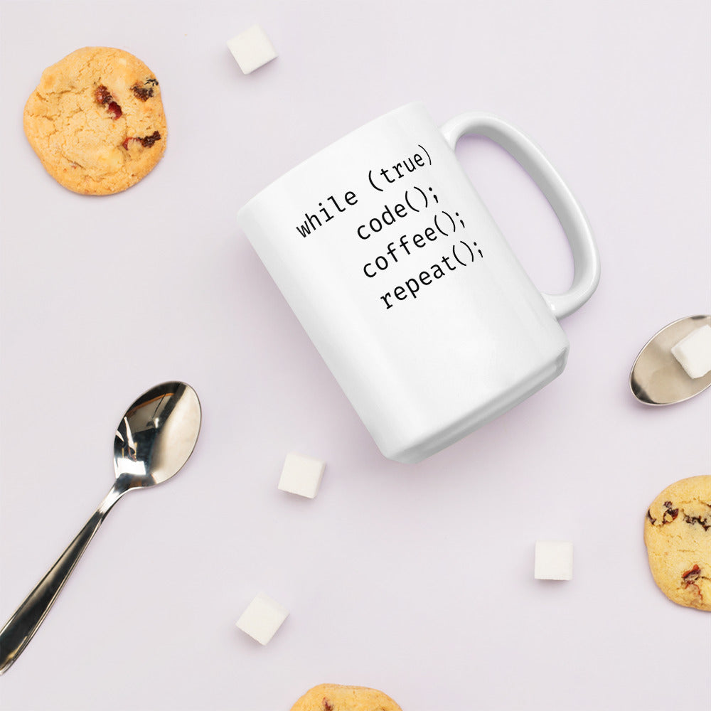 White 15oz tech humor coffee mug featuring slogan “Code. Coffee. Repeat.” in code with handle on the right with biscuits around.