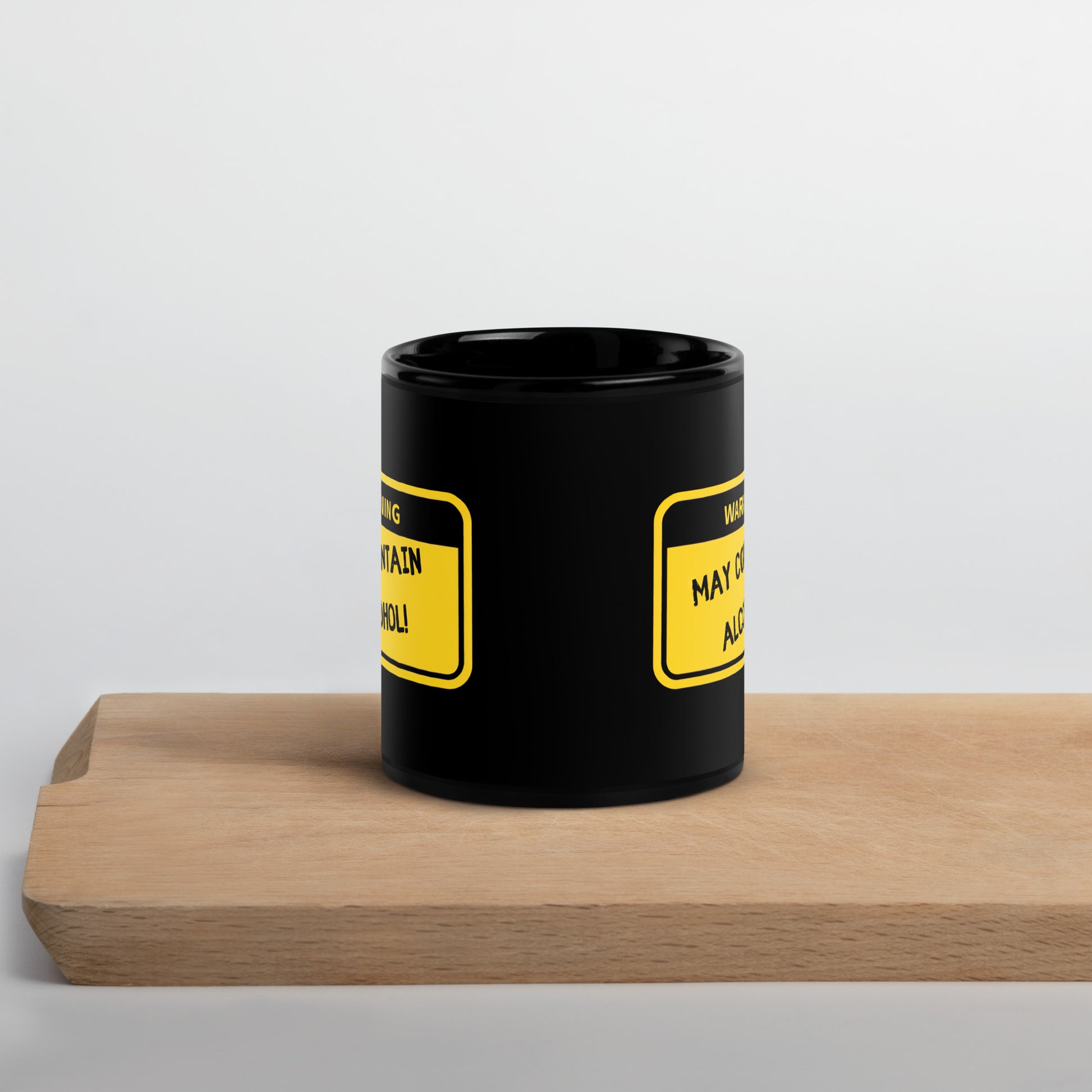 Black 11oz tech humor coffee mug with name label that says, ‘Warning: May Contain Alcohol!’ on cutting board.