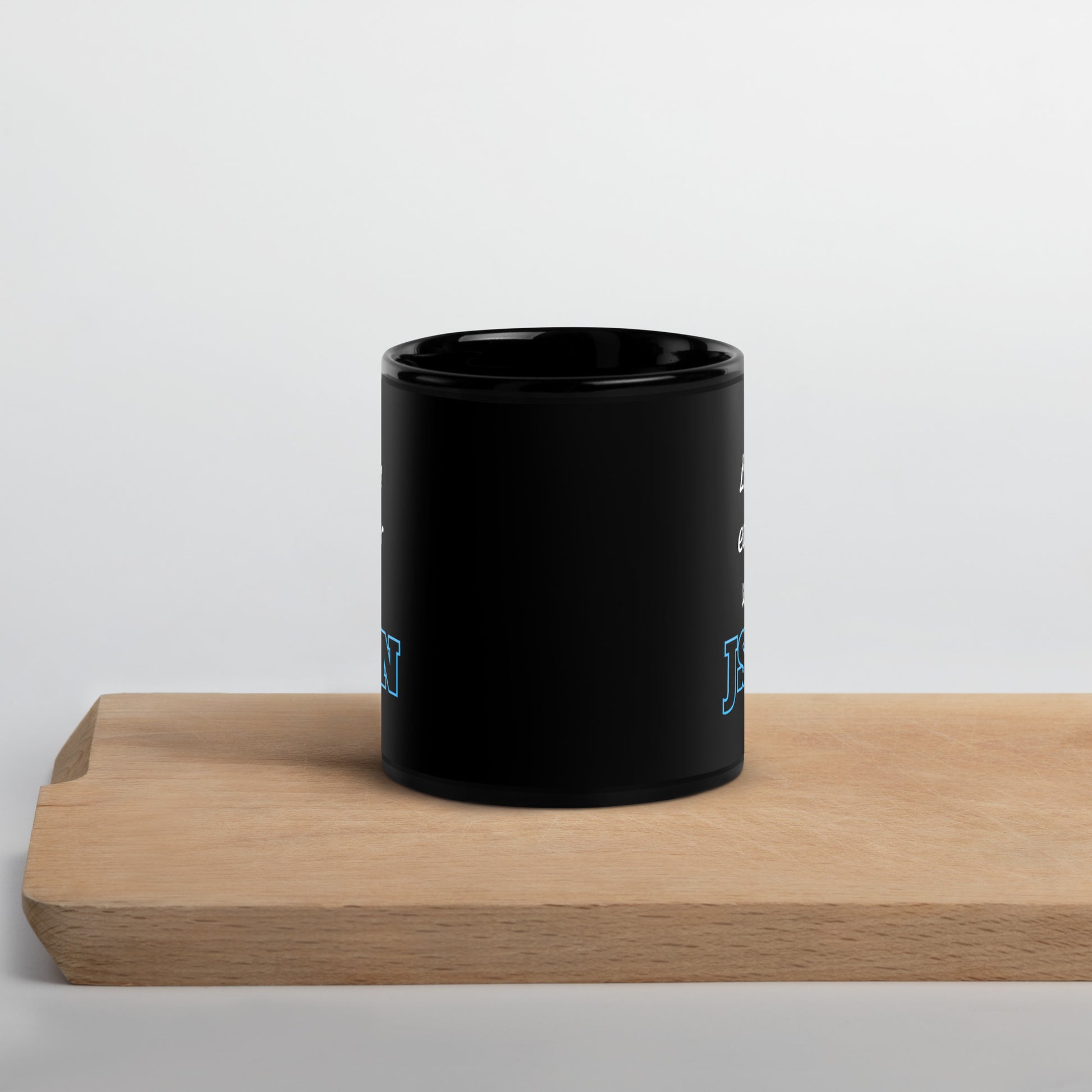 Black 11oz tech humor coffee mug with design that reads ‘Life's easier with JSON’ sitting on cutting board.