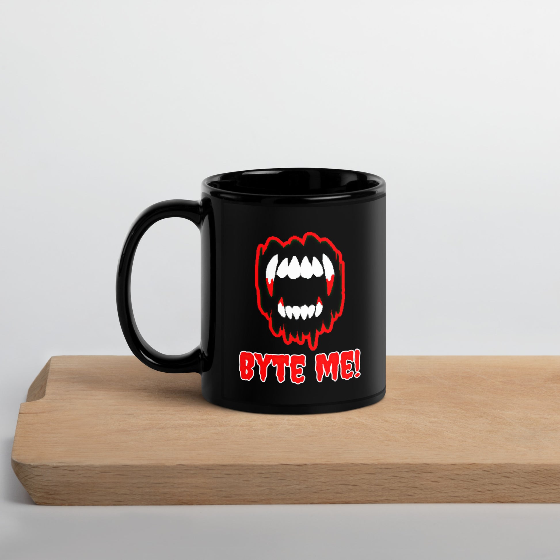 Black 11oz tech humor Halloween coffee mug featuring slogan “Byte Me!” under pixelated vampire fangs with handle on the left.