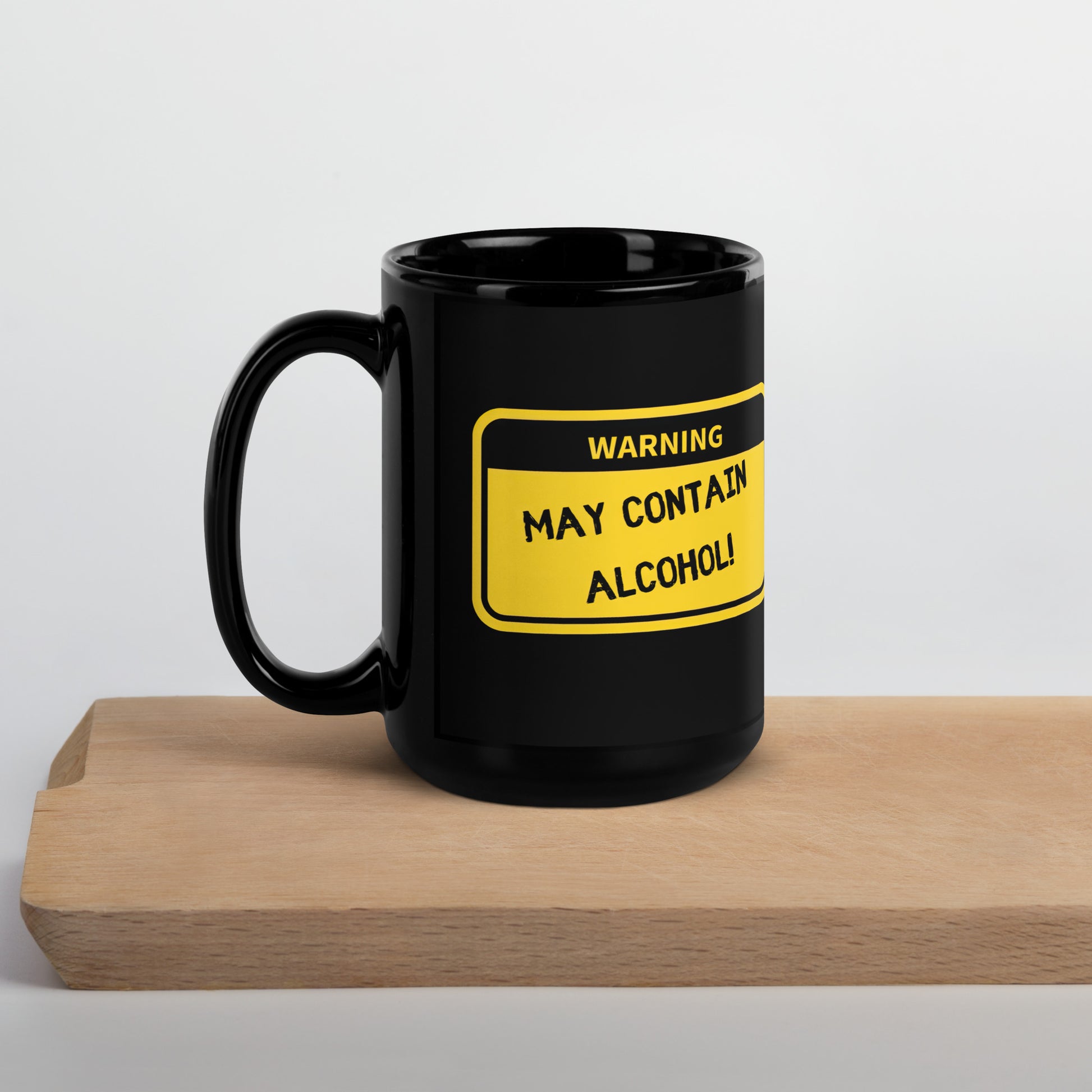 Black 15oz tech humor coffee mug with name label that says, ‘Warning: May Contain Alcohol!’ with handle on left on wooden board.