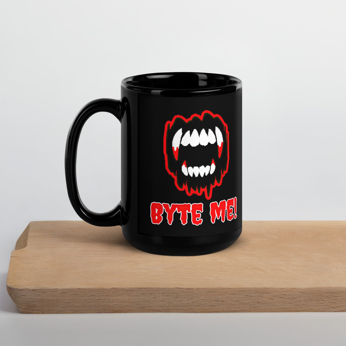 Black 15oz tech humor Halloween coffee mug featuring slogan “Byte Me!” under pixelated vampire fangs with handle on the left.