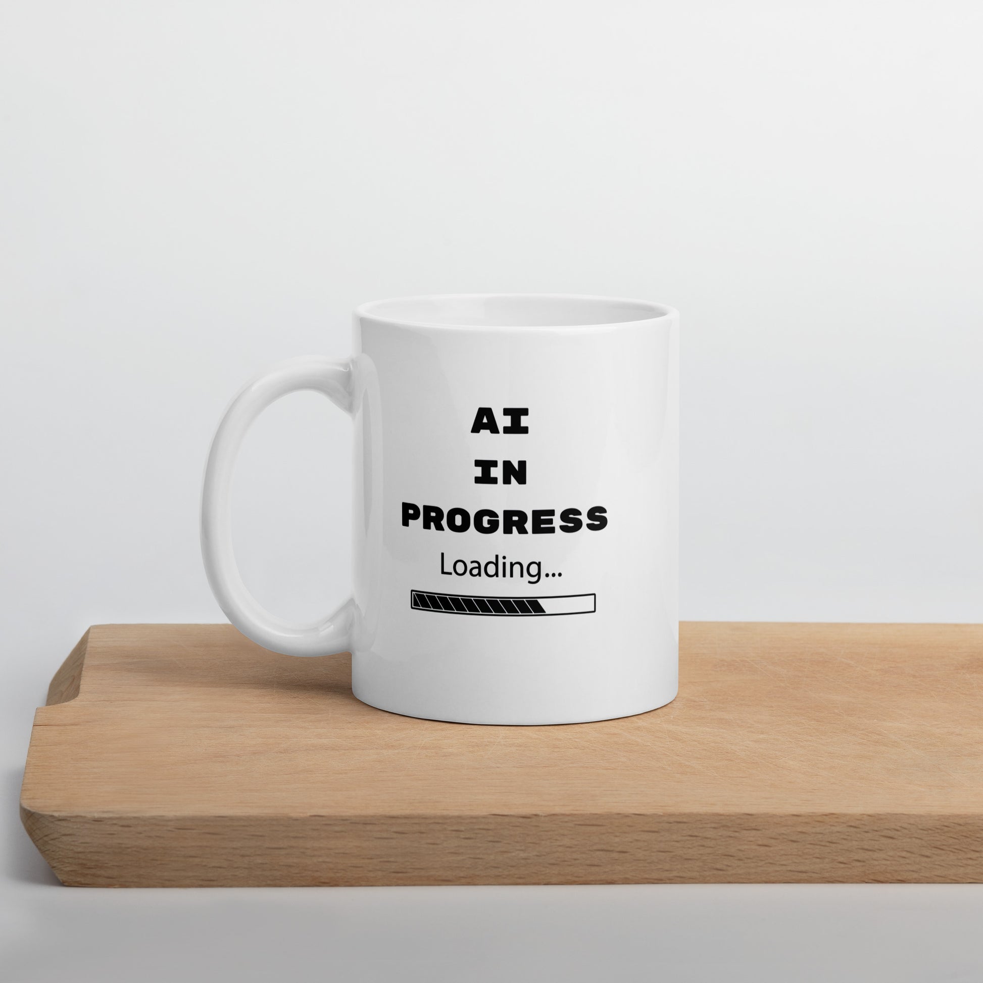 White 11oz tech humor and AI coffee mug featuring slogan “AI in Progress” with handle on the left.