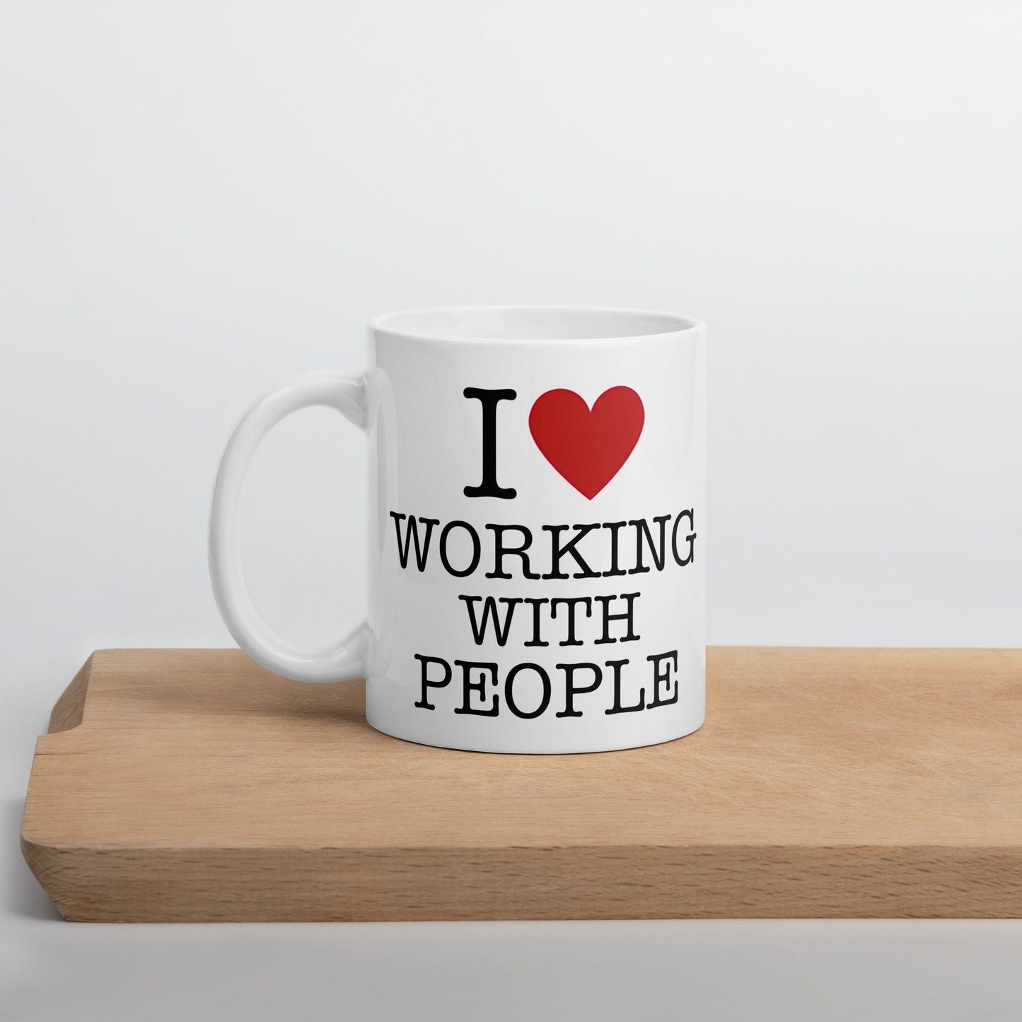 White 11oz tech humor coffee mug with an I Love NY style design that reads ‘I Love Working With People’ with handle on left.