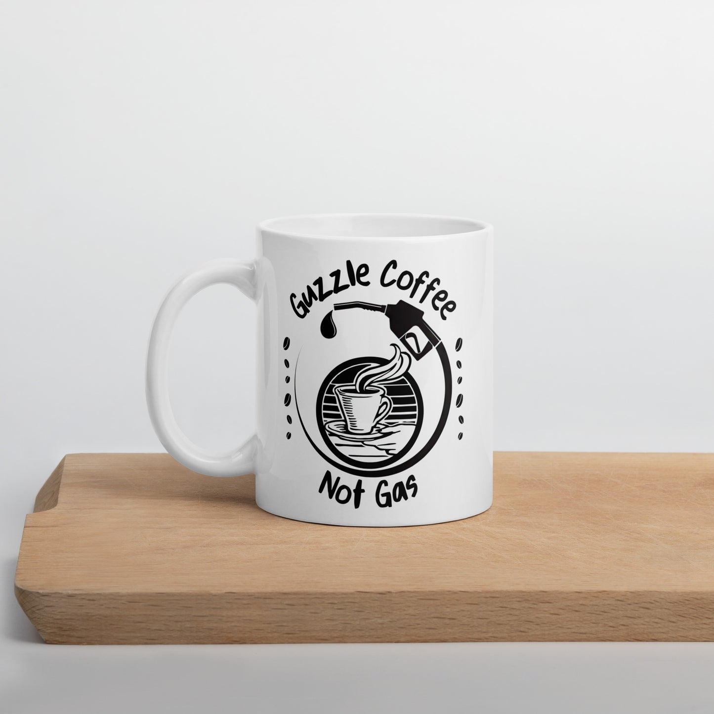 White 11oz EV themed coffee mug with a gas pump over a coffee cup and slogan ‘Guzzle Coffee, Not Gas’ on cutting board.