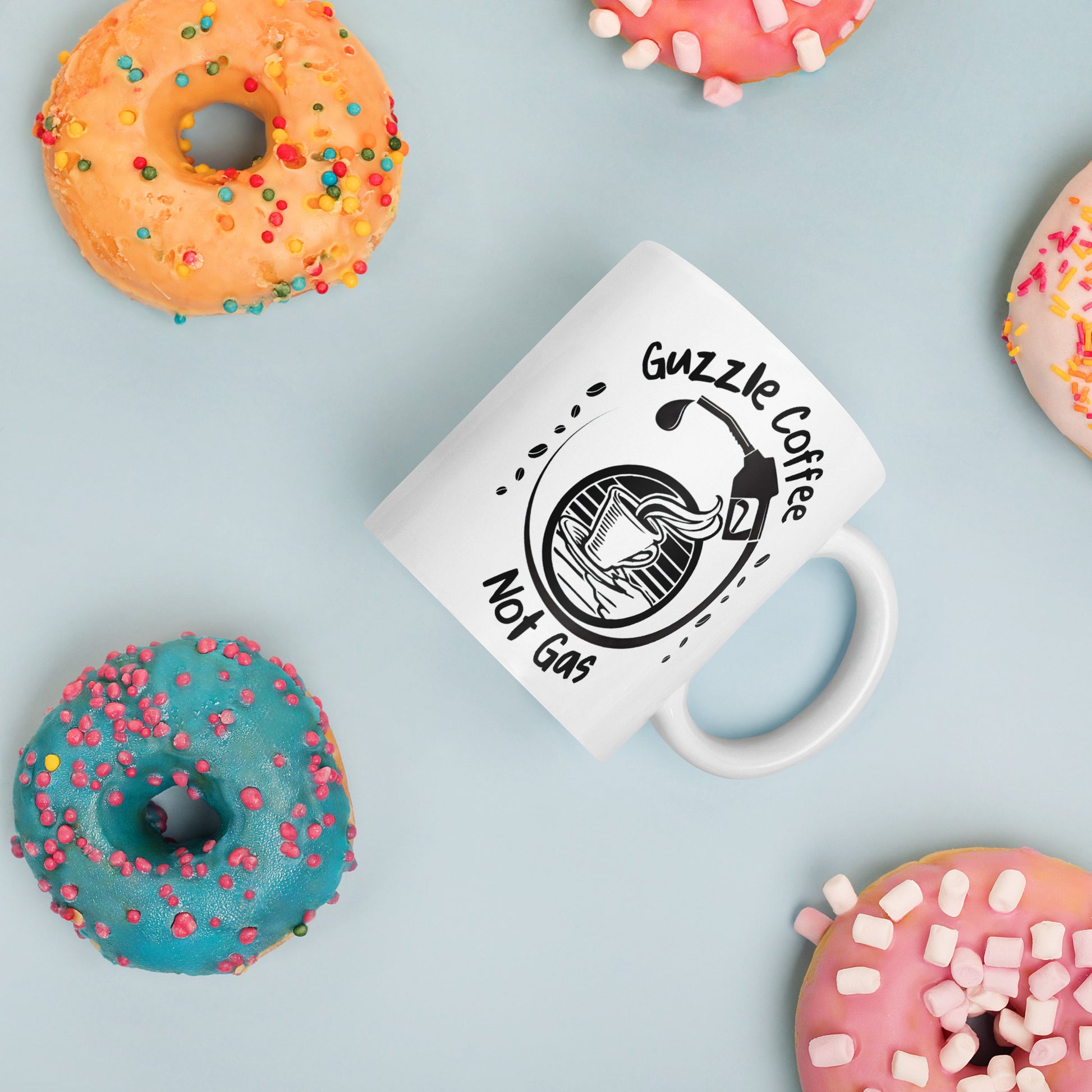 White 11oz EV themed coffee mug with a gas pump over a coffee cup and slogan ‘Guzzle Coffee, Not Gas’ surrounded by donuts.