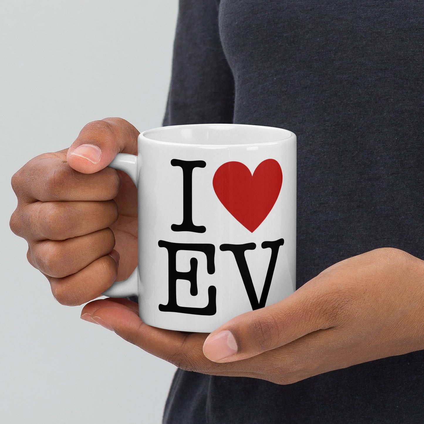 White 11oz EV themed coffee mug with an I Love NY type slogan ‘I Love EV’ with handle on left held by a man.