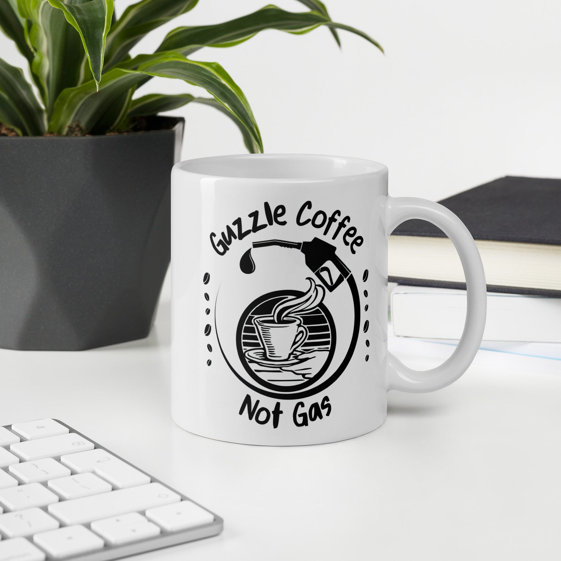 White 11oz EV themed coffee mug with a gas pump over a coffee cup and slogan ‘Guzzle Coffee, Not Gas’ with handle on right on desk.