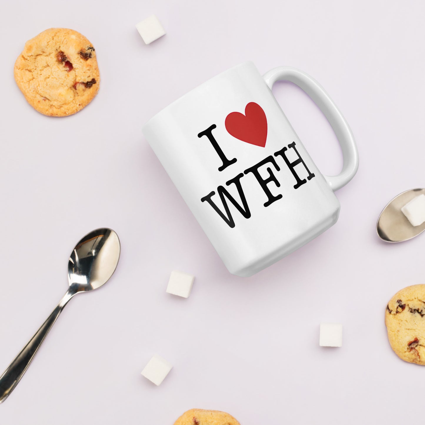 White 11oz tech humor coffee mug with an I Love NY style design that reads ‘I Love WFH’ with handle on right surrounded by biscuits and spoons.