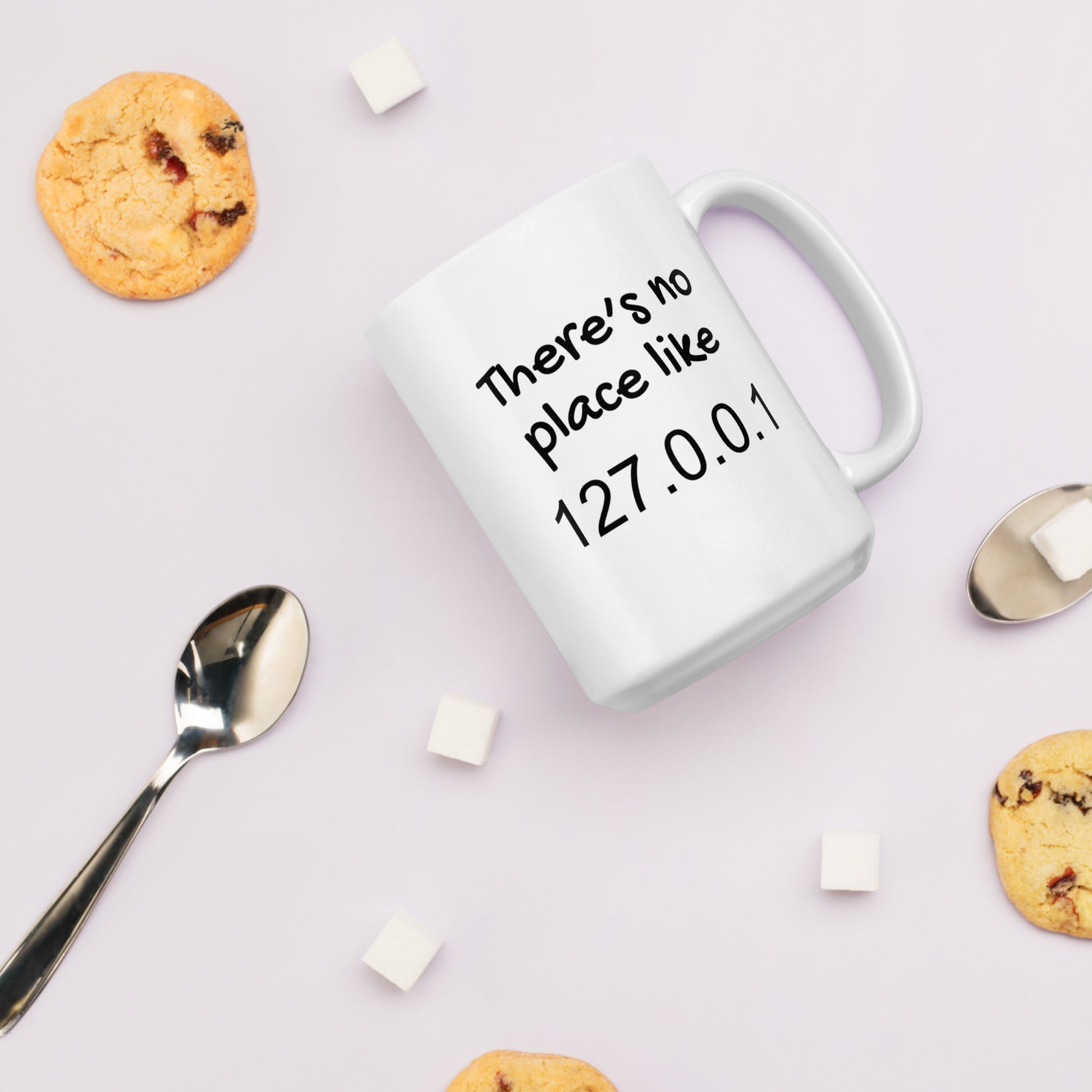 White 15oz tech humor coffee mug with the slogan ‘There's no place like 127.0.0.1’ with handle on right.