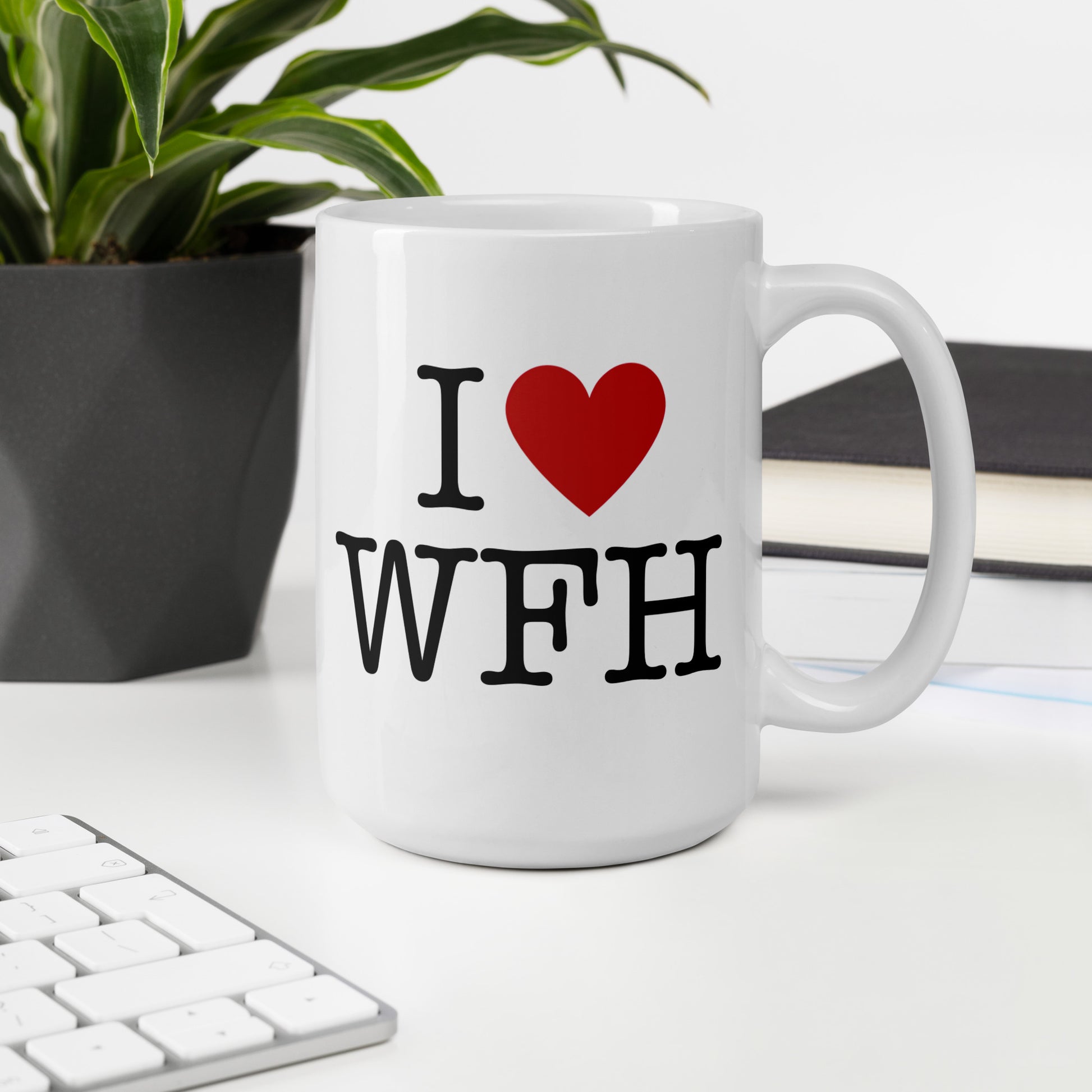 White 15oz tech humor coffee mug with an I Love NY style design that reads ‘I Love WFH’ with handle on left on work desk.